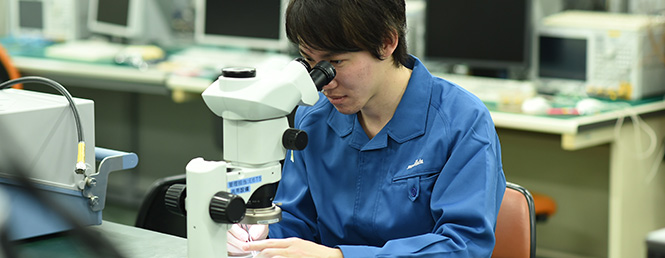 通信センサ事業本部 高周波デバイス事業部 SAW商品部 開発課 所属社員が顕微鏡を覗いている様子。